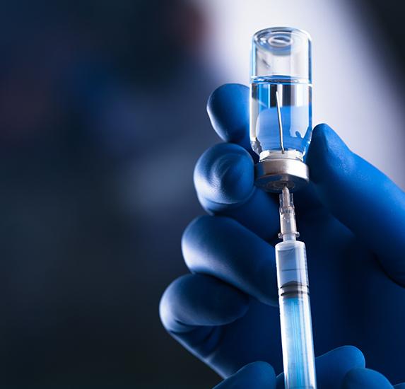 A gloved hand holding a powdered a syringe and Vivitrol