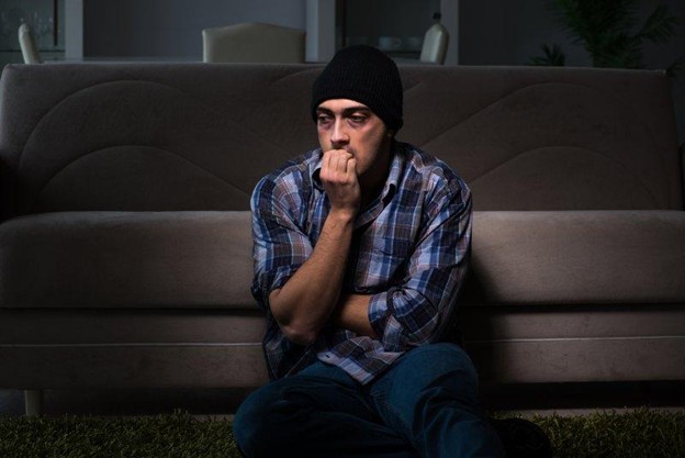 A drug addict sitting in front of a sofa 